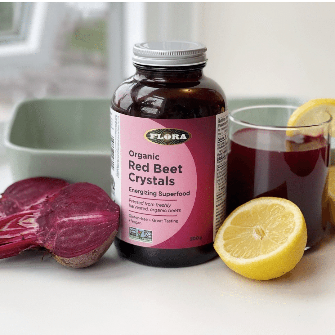 Flora organic red beet crystals energizing superfood on a table right next to a beet, a lime and a glass with the product dissolved in water